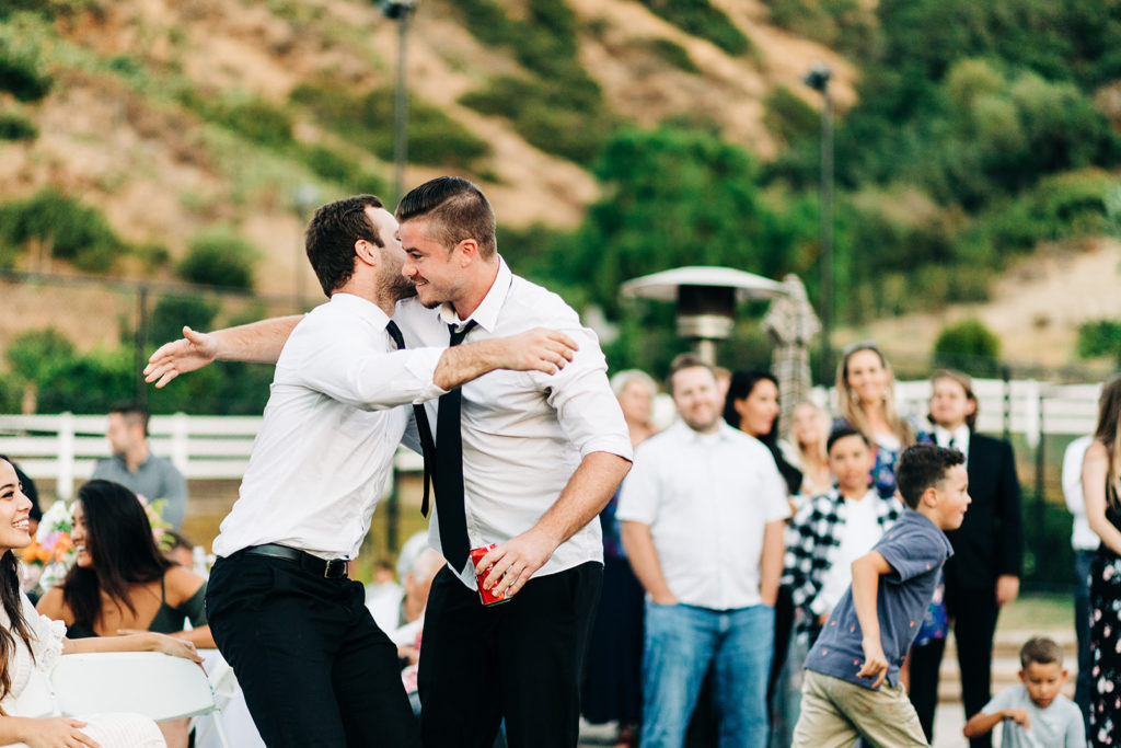 Camarillo wedding photography ; groom hugs groomsman at reception