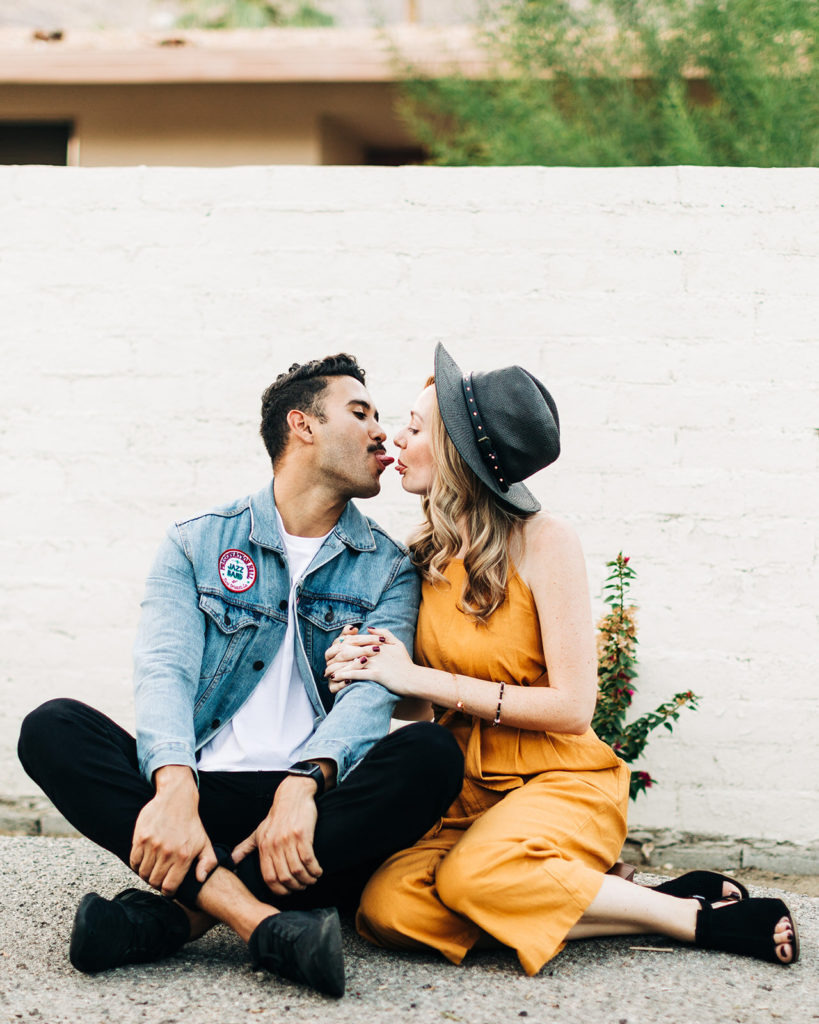 southern california engagement photos; couple sitting together while man sticks his tongue out