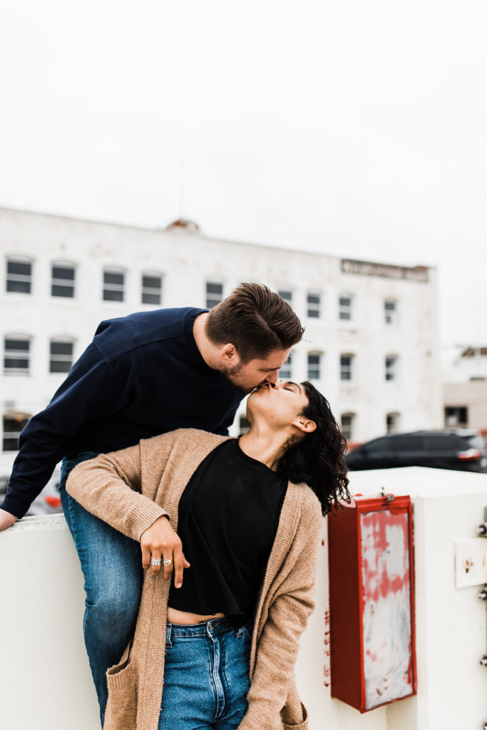southern california engagement photos; gay couple kissing sitting on a parking structure in santa ana