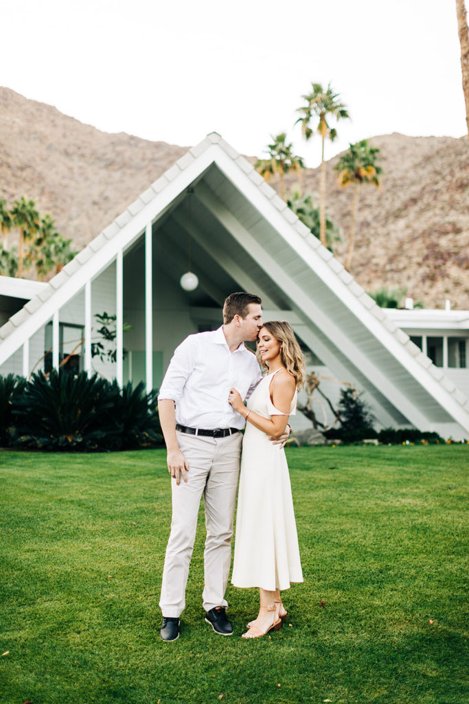 southern california engagement photos; couple hugging in front of mid century modern house in palm springs