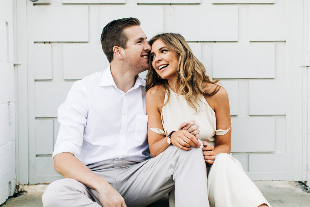 southern california engagement photos; couple sitting on the curb smiling in palm springs