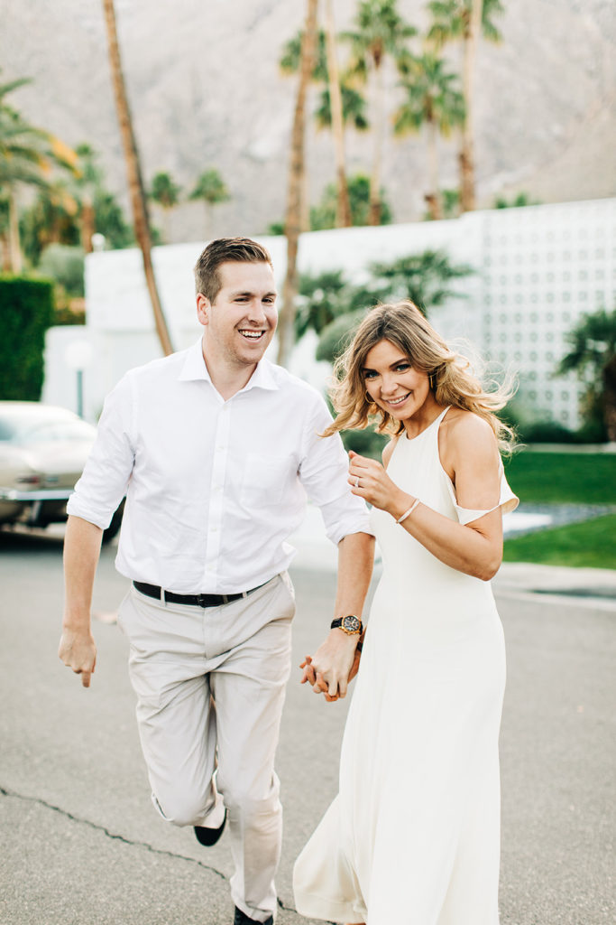 southern california engagement photos; couple holding and hands and running in palm springs