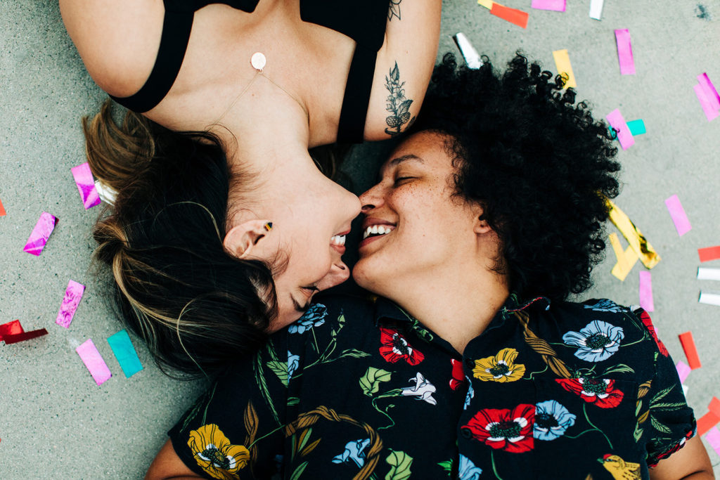 southern california engagement photos; lesbian couple laying on the ground facing each other and smiling