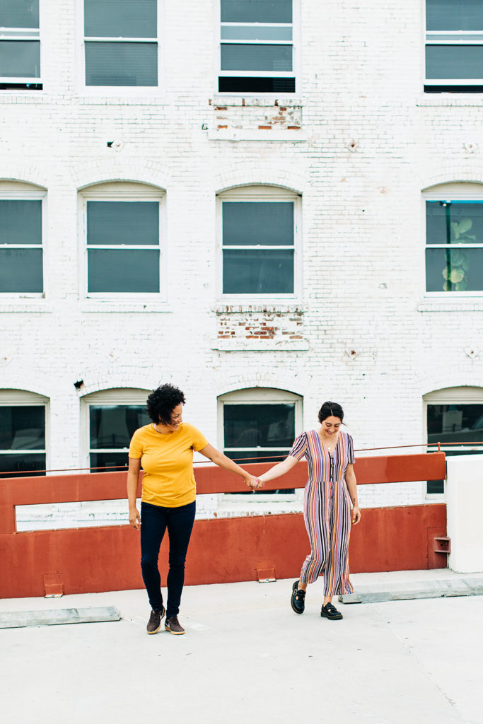 southern california engagement photos; lesbian couple holding and hands and walking in santa ana
