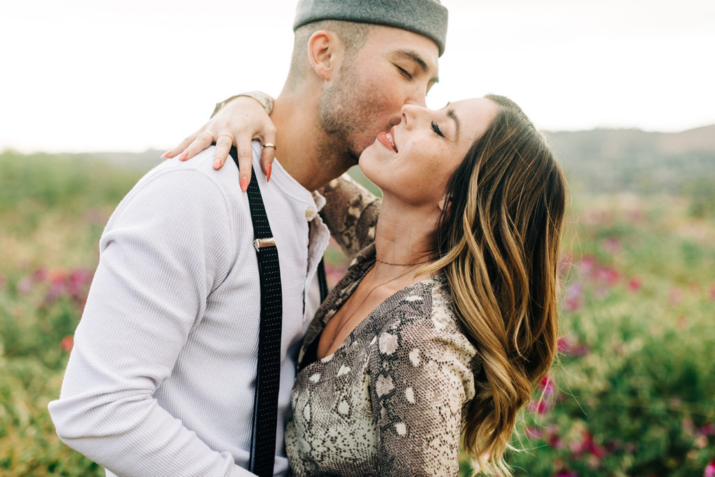 orange county engagement photos; man kissing woman on the cheek in a flower field