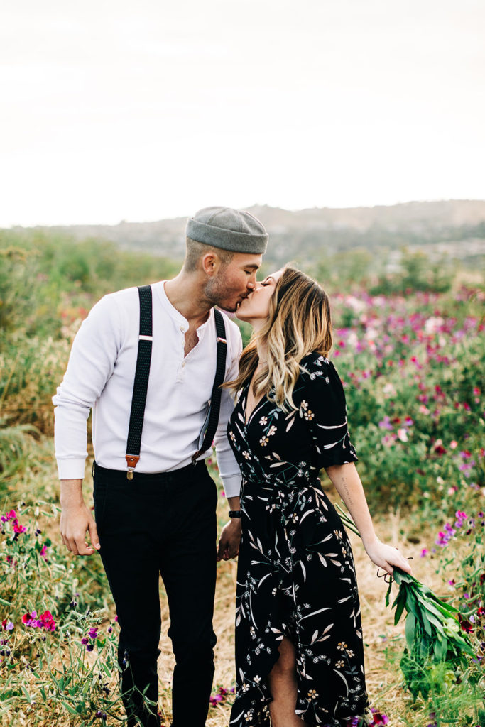 orange county engagement photos; couple kissing while walking in a flower field