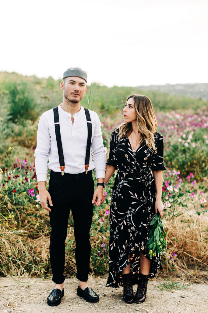 orange county engagement photos; woman looking at man while holding hands in a flower field