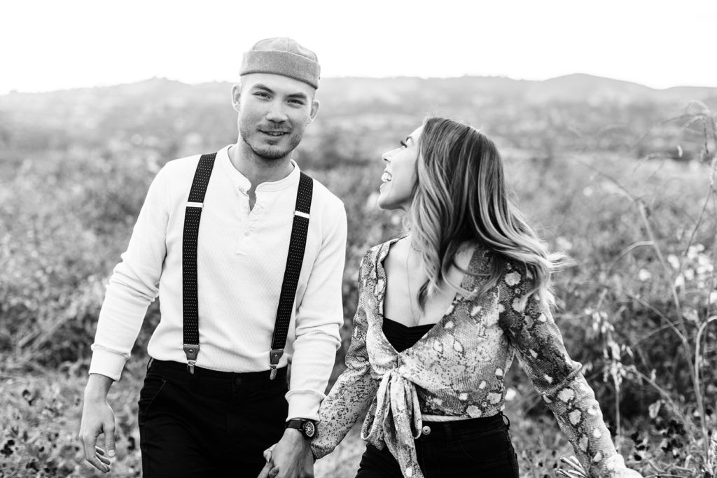 orange county engagement photos; black and white photo of a couple kissing while walking in a flower field