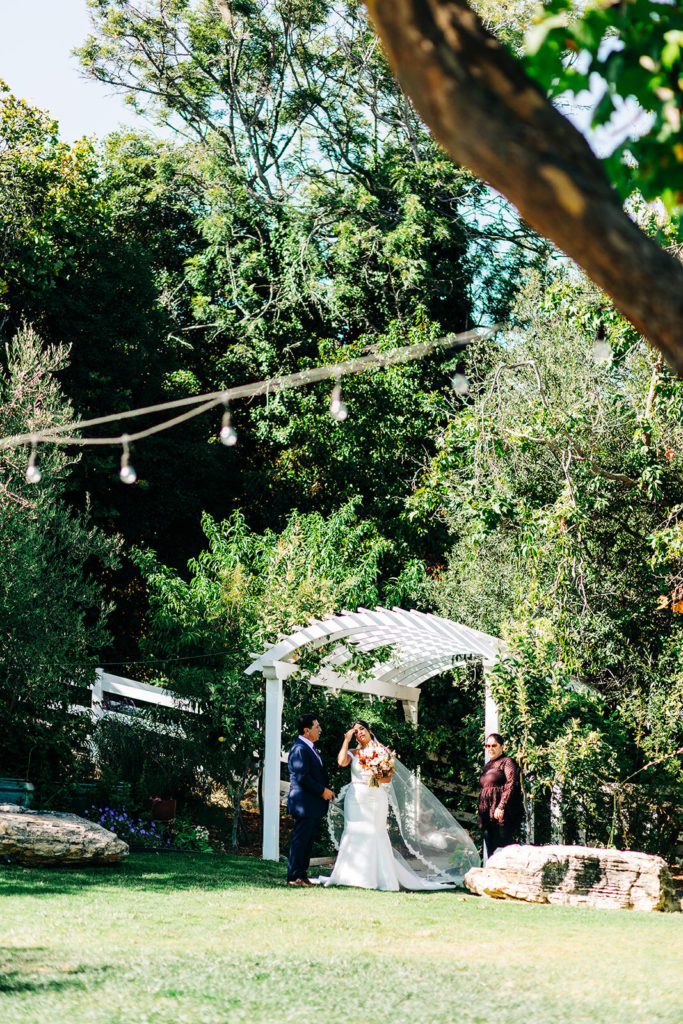 The Madonna Inn In San Luis Obispo, CA wedding photography; bride and groom standing under the white arch