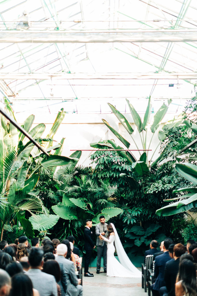 Valentine DTLA Wedding, Los Angeles wedding photographer; wide angle shot of a bride and groom at their wedding venue with lots of green plants in los angeles