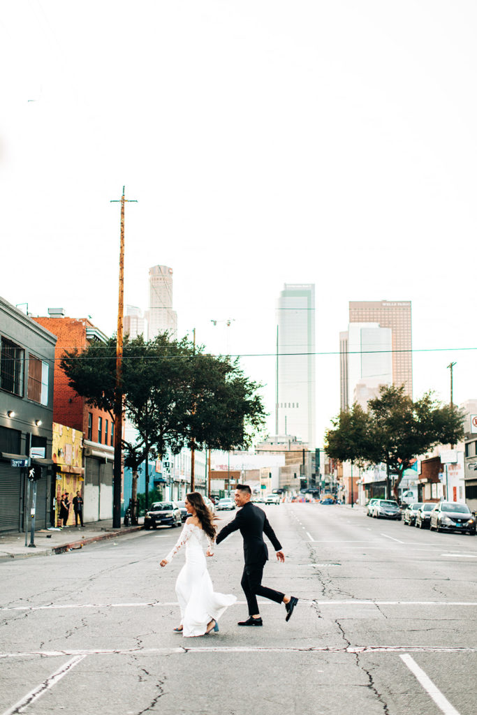 Valentine DTLA Wedding, Los Angeles wedding photographer; bride and groom running across a street in downtown los angeles while holding hands
