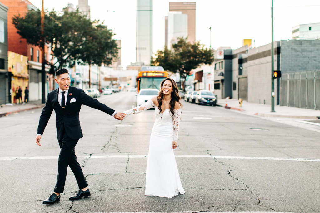 Valentine DTLA Wedding, Los Angeles wedding photographer; groom guiding bride across the street as she laughs