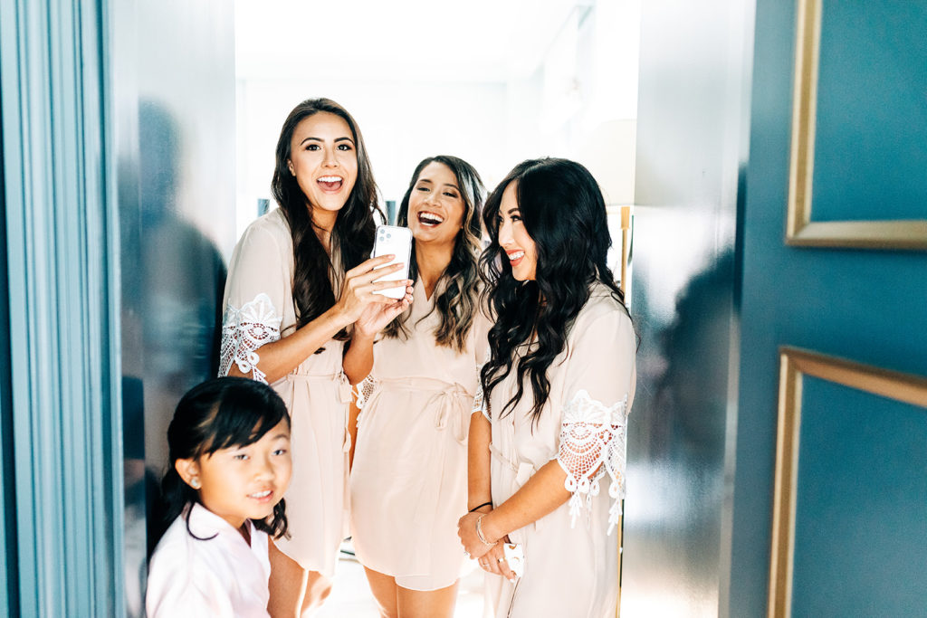 Valentine DTLA Wedding, Los Angeles wedding photographer; bridesmaids laughing and taking pictures with an iphone 11 pro
