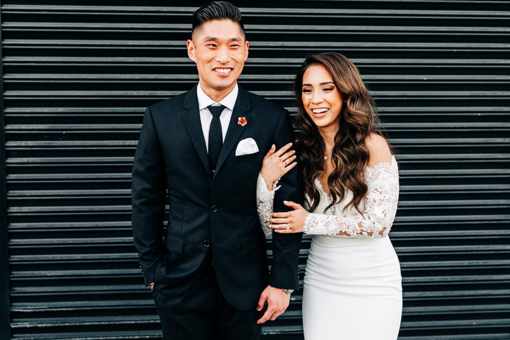 Valentine DTLA Wedding, Los Angeles wedding photographer; bride and groom smiling and laughing in front of a black garage door