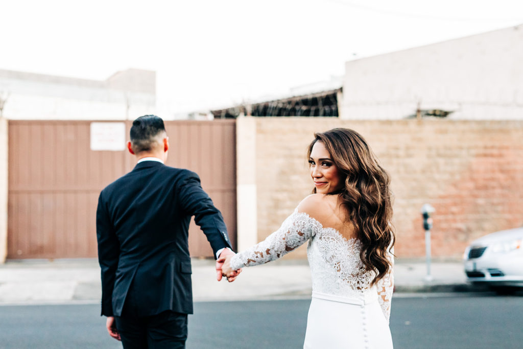 Valentine DTLA Wedding, Los Angeles wedding photographer; bride and groom walking across the street as the bride turns back to look at the camera