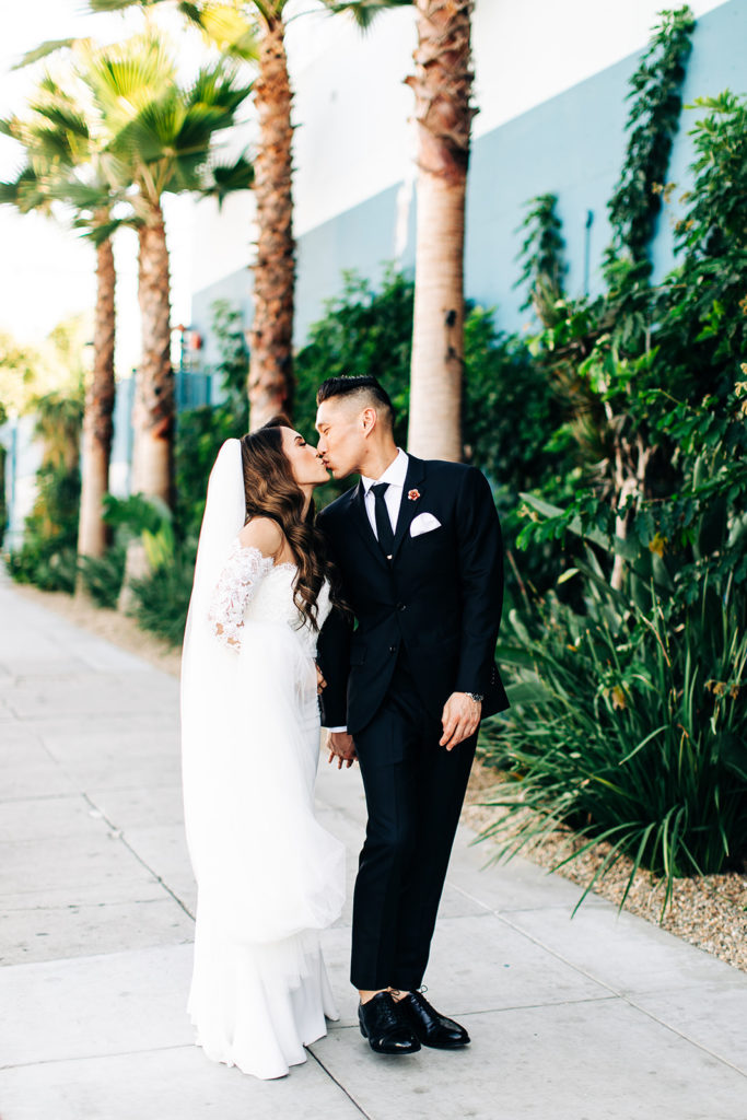 Valentine DTLA Wedding, Los Angeles wedding photographer; bride and groom kissing while they walk down a sidewalk