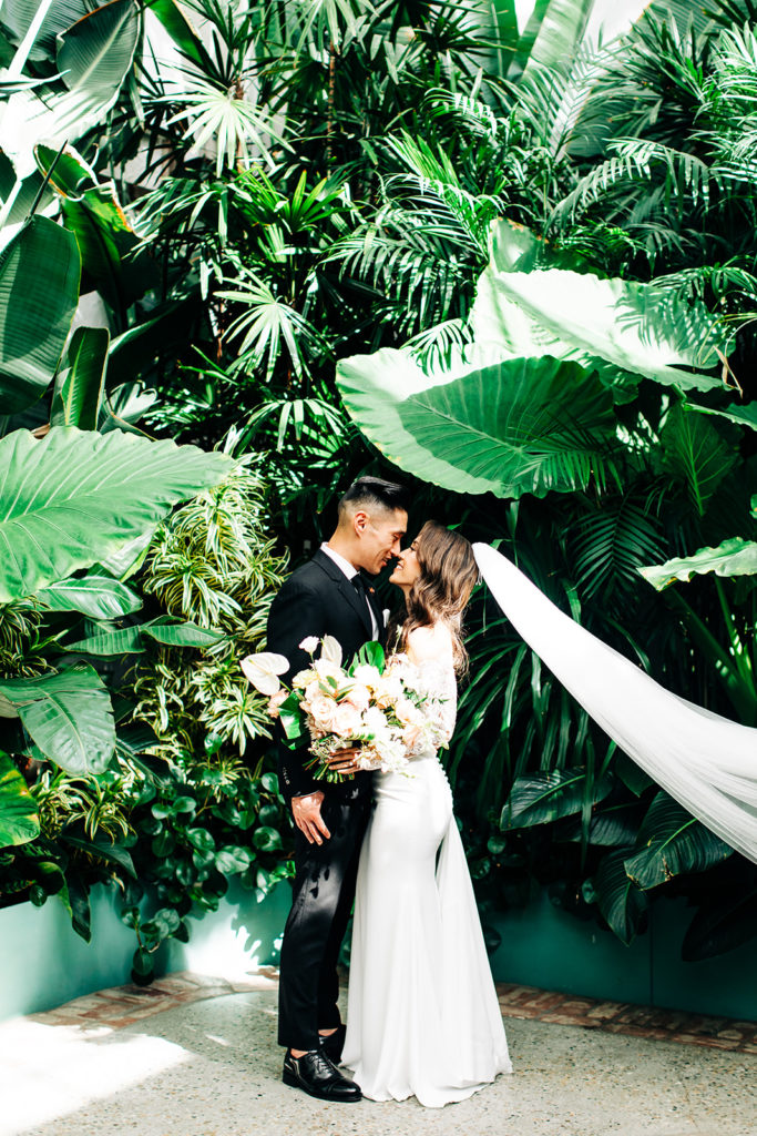 Valentine DTLA Wedding, Los Angeles wedding photographer; bride and groom looking at each other in front of lots of lush green plants