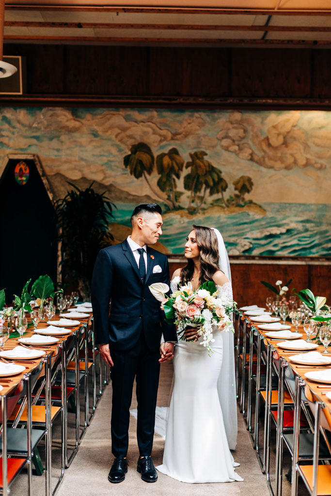 Valentine DTLA Wedding, Los Angeles wedding photographer; bride and groom smiling at each other while standing in between two dinner tables