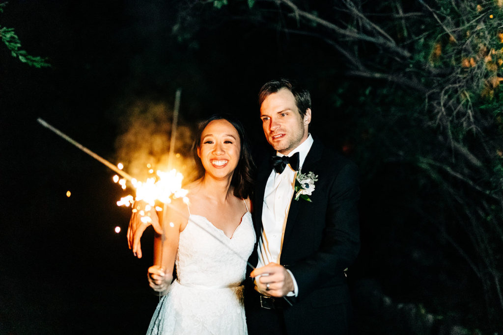 The Gold Mountain Manor In Big Bear, CA wedding photography; bride holding sparkler with her groom besides her