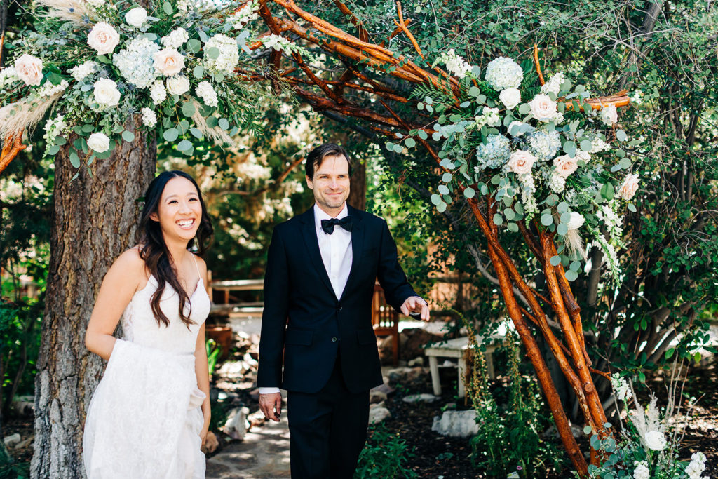 The Gold Mountain Manor In Big Bear, CA wedding photography; bride and groom standing in front of wooden arch