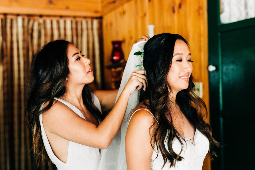 The Gold Mountain Manor In Big Bear, CA wedding photography; bride getting ready with the help f bridesmaid
