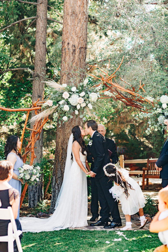 The Gold Mountain Manor In Big Bear, CA wedding photography; bride and groom kissing in front of tall trees