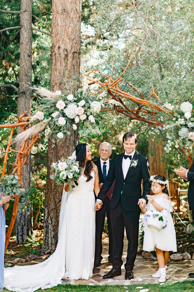 The Gold Mountain Manor In Big Bear, CA wedding photography; bride and groom standing in front of the wooden arch