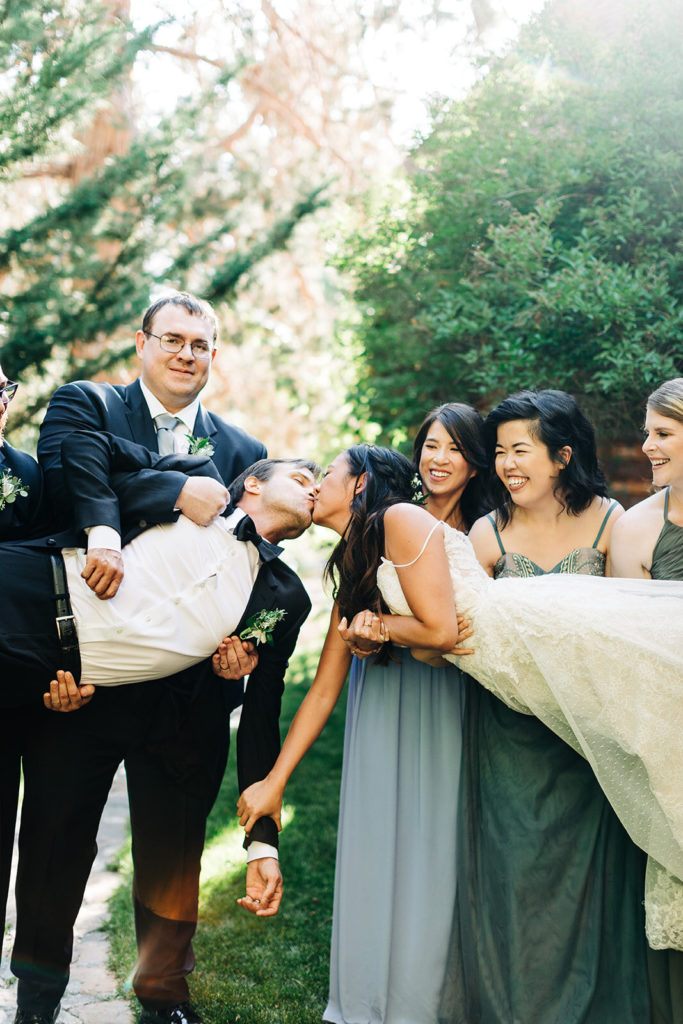 The Gold Mountain Manor In Big Bear, CA wedding photography; bride and groom kising each other in a unique way both lifted up by their friends and bridesmaid