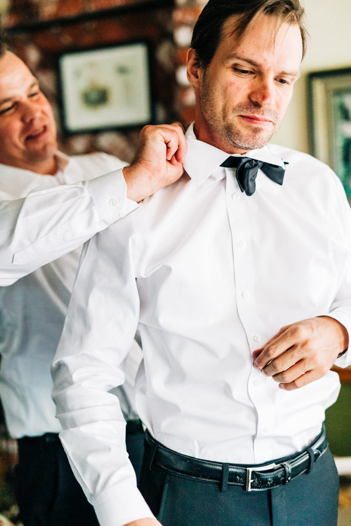 The Gold Mountain Manor In Big Bear, CA wedding photography; groom's collar being adjusted by a groomsman