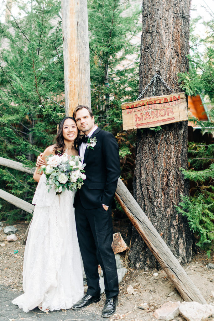 The Gold Mountain Manor In Big Bear, CA wedding photography; bride and groom standing on the path in front of tall trees