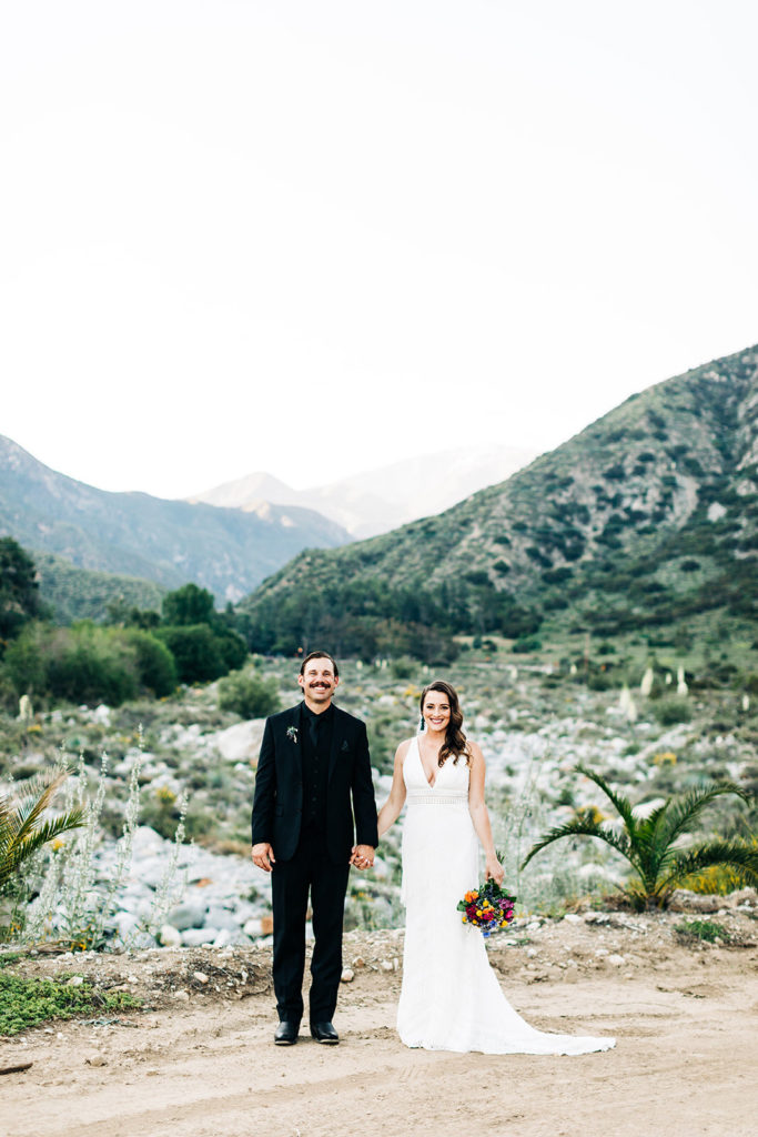 Sweet Pea Ranch In Upland, CA wedding photography; bride and groom holding hands on hill