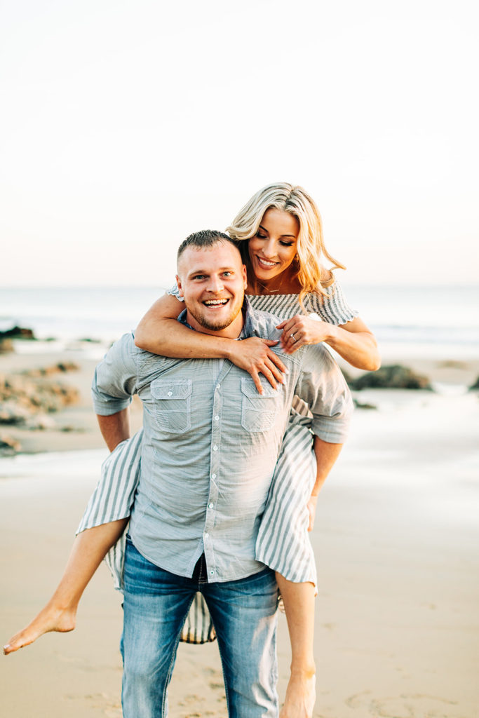 crystal cove beach engagement photos in orange county; woman jumping on man's back at the beach