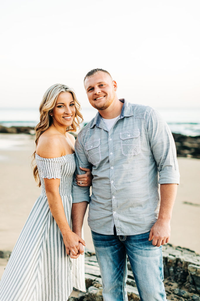 crystal cove beach engagement photos in orange county; couple holding hands and smiling at the beach