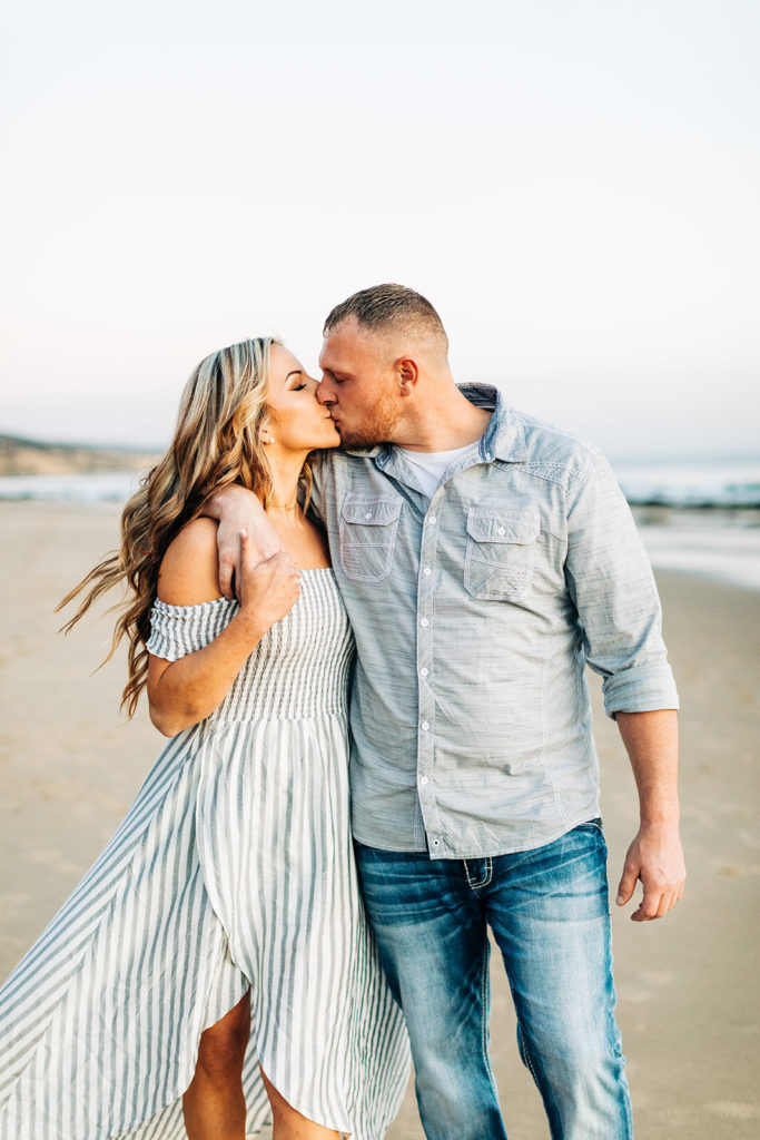 crystal cove beach engagement photos in orange county; couple kissing at the beach while walking