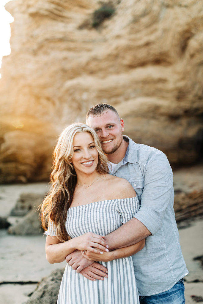 crystal cove beach engagement photos in orange county; couple hugging on the beach and smiling