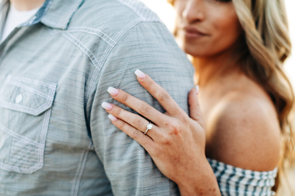crystal cove beach engagement photos in orange county; close up of an engagement ring on a woman's hand as it rests on a man's shoulder