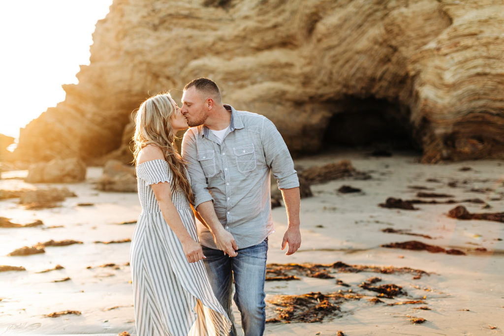 crystal cove beach engagement photos in orange county; couple walking on the beach while kissing