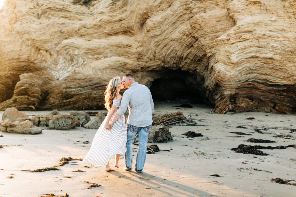 crystal cove beach engagement photos in orange county; couple walking on the beach and kissing