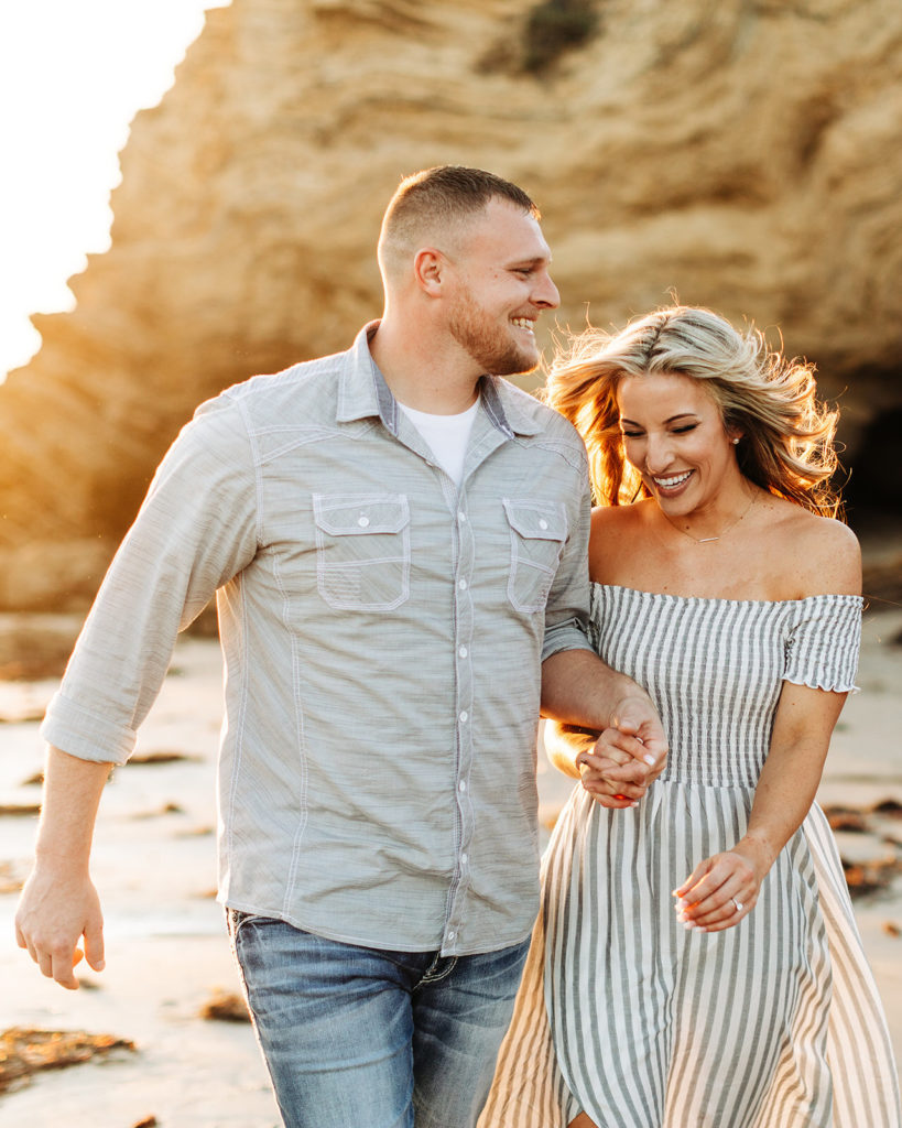 crystal cove beach engagement photos in orange county; couple running while holding hands at the beach