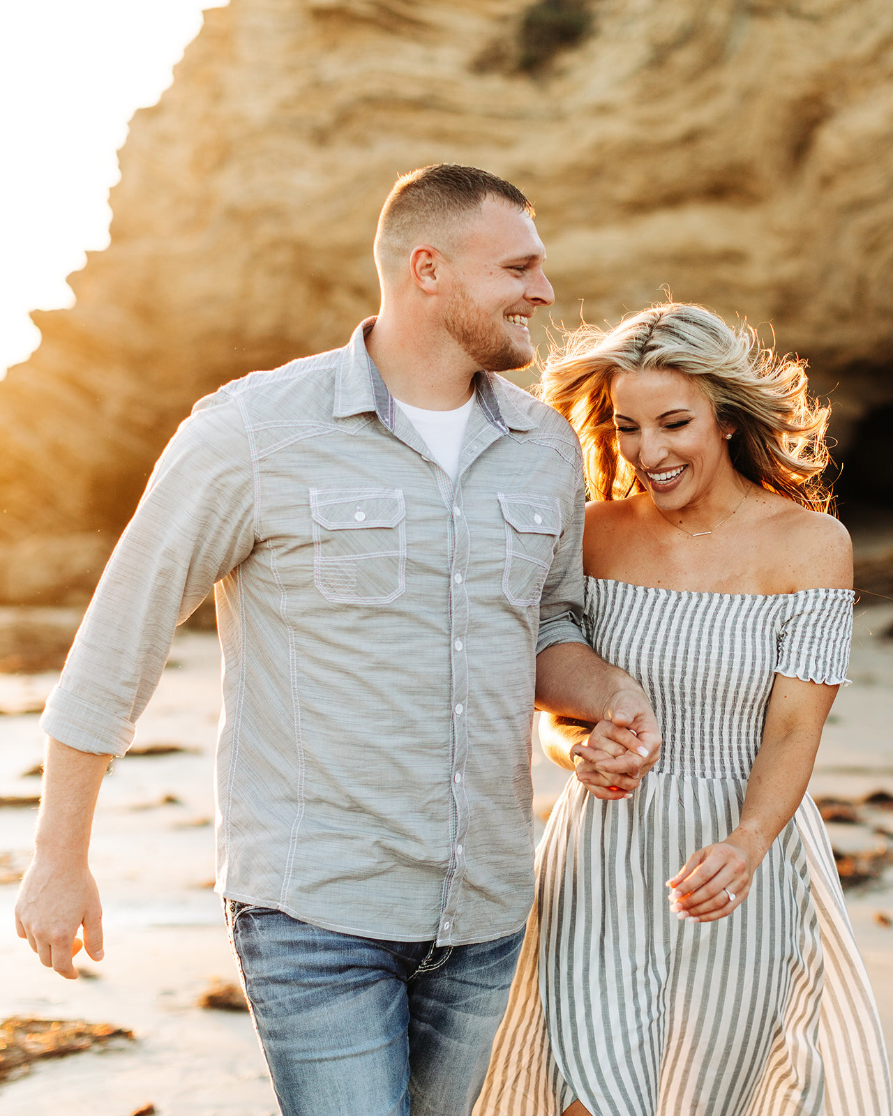 southern california engagement photos; couple walking and holding hands at the beach
