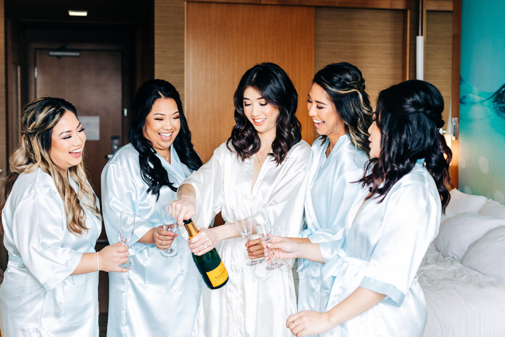 Pasea Hotel & Spa in Huntington Beach, CA wedding photography; bride opening the champagne bottle with bridesmaids