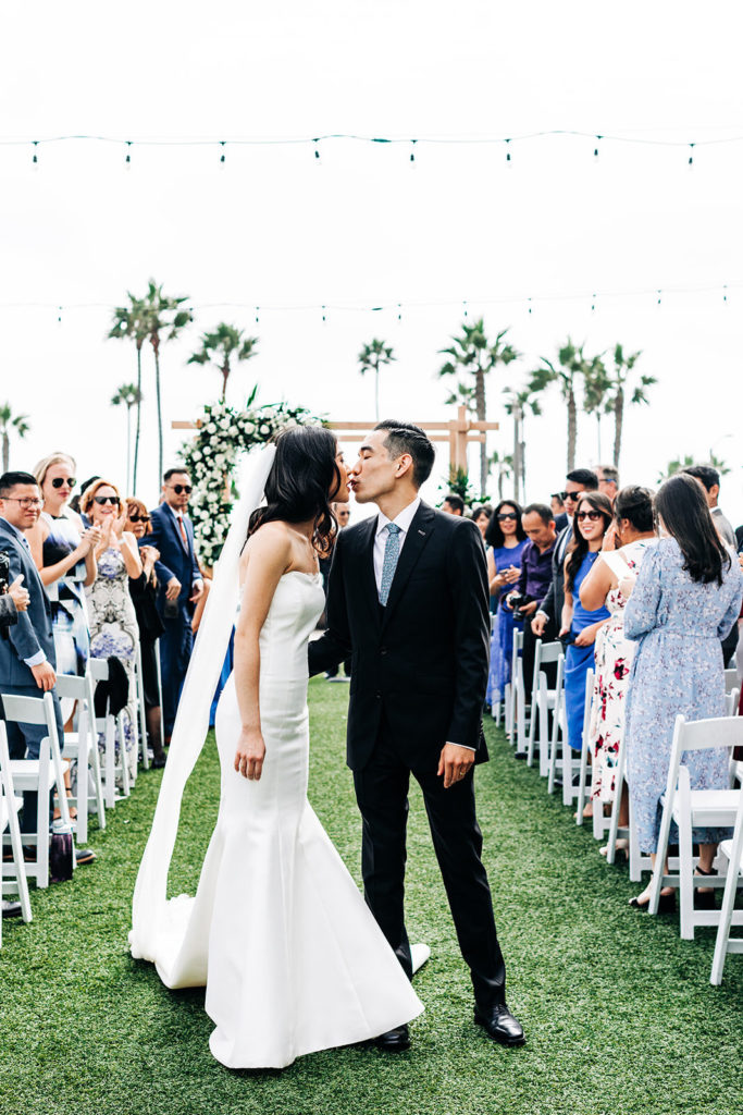 Pasea Hotel & Spa in Huntington Beach, CA wedding photography; bride and groom kissing in between the aisle