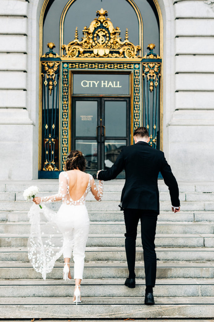 City Hall in San Francisco, CA wedding photography; bride and groom going upstairs towards City Hall entrance