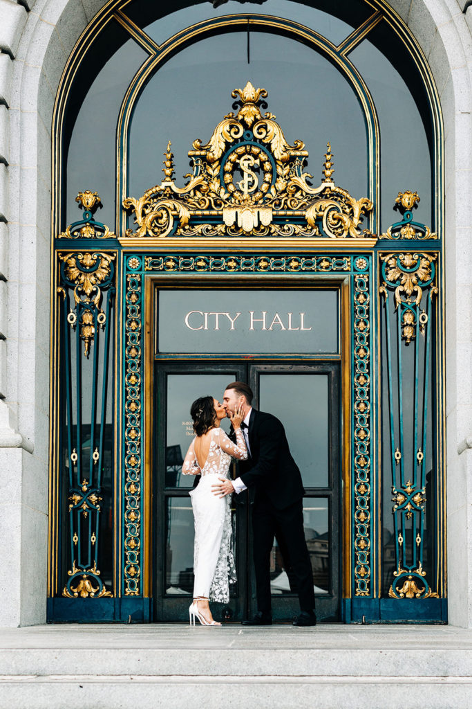 City Hall in San Francisco, CA wedding photography; bride and groom kissing at the City Hall entrance