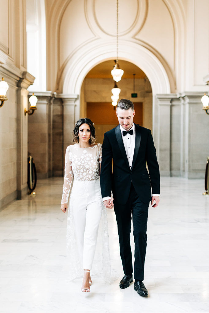 City Hall in San Francisco, CA wedding photography; bride and groom coming, holding each other's hands