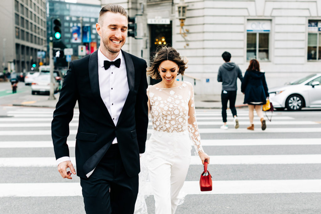 City Hall in San Francisco, CA wedding photography; bride and groom crossing the road while holding hands