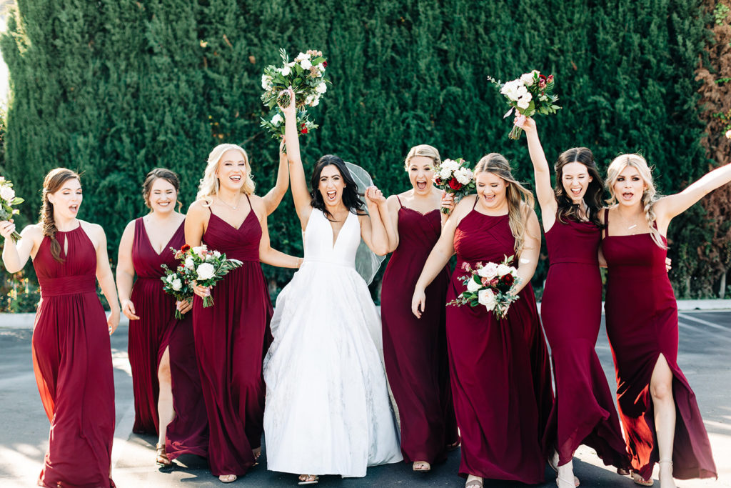 Colony house in Anaheim, CA wedding photography; bride with bridesmaids with flowers and green wall background