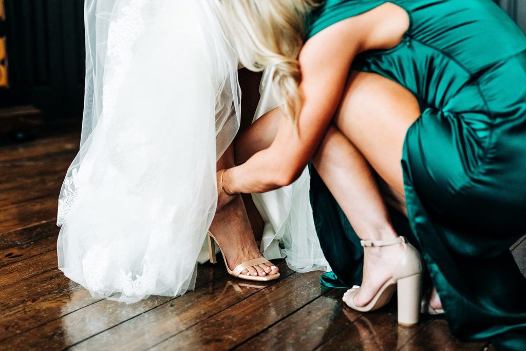 Avalon Legacy Ranch wedding photography; bride having her footwear adjusted