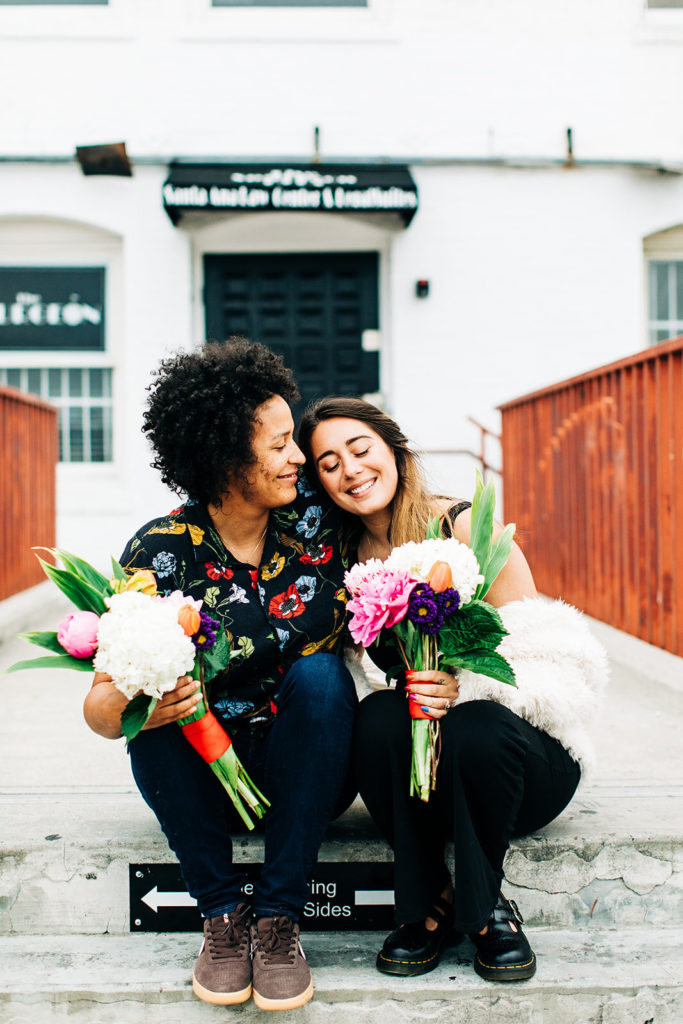 southern california engagement photos; lesbian couple holding flowers and sitting together