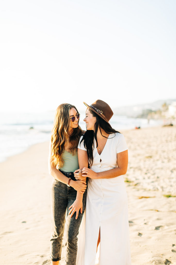lesbian couple hugging and smiling on the beach in laguna beach, ca